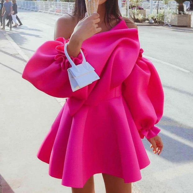 Bright pink mini party dress with one shoulder and puff sleeves, ruffle skirt, and zipper detail