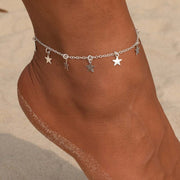 Simple star charm fashion anklet on ankle with sandy beach background