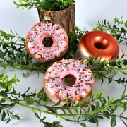 Christmas decorations pendant donut-shaped glass ornaments with pink icing and sprinkles in green foliage setting