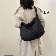 Woman wearing black quilted Warm Totes Shoulder Bag over beige coat