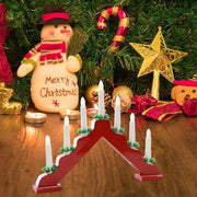 Wooden Christmas window decoration candlesticks with white candles and red base surrounded by festive ornaments
