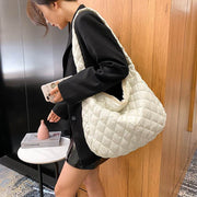 Woman carrying a white quilted nylon warm totes shoulder bag with soft handle in a black outfit
