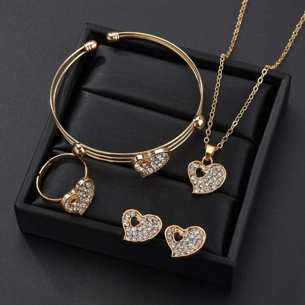 Gold love jewelry set with heart-shaped crystal earrings, ring, necklace, and bracelet in black box