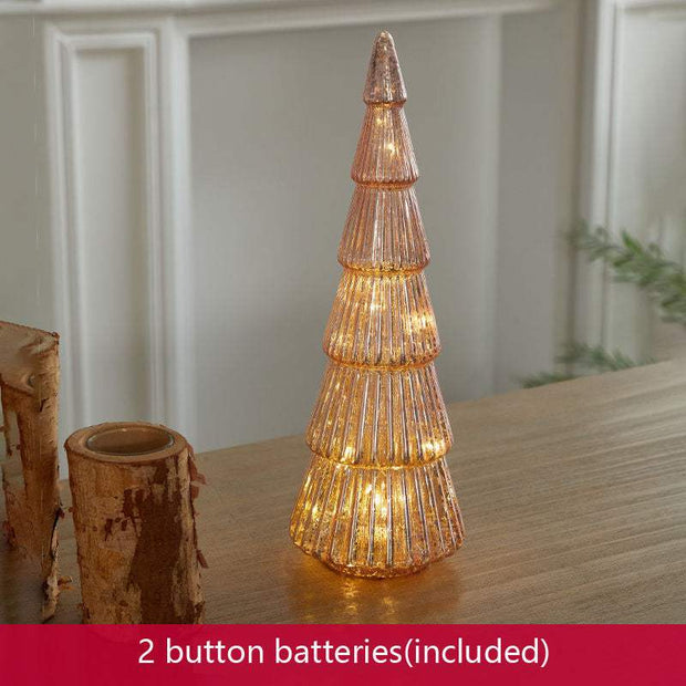 Glowing geometric glass Christmas tree table decoration with warm lights on wooden surface