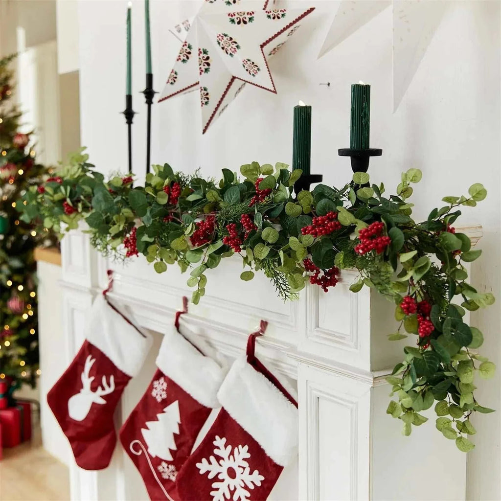 6.3ft artificial Christmas garland with green leaves and red berries hanging on a white fireplace mantle decorated with red and white stockings and green candles Christmas decoration