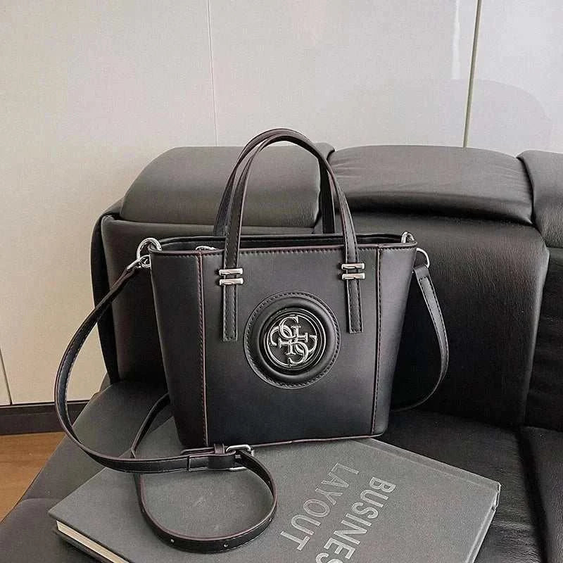 Stylish large capacity black leather crossbody bag with vintage designer logo and adjustable strap on sofa