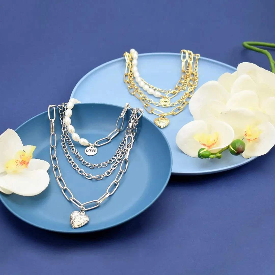 Jester Necklace - Dazzling Chain with Pearls & Heart displayed on blue plates with flowers.