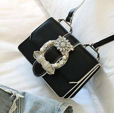 Black fashion designer bag with diamond-studded lock and shoulder strap
