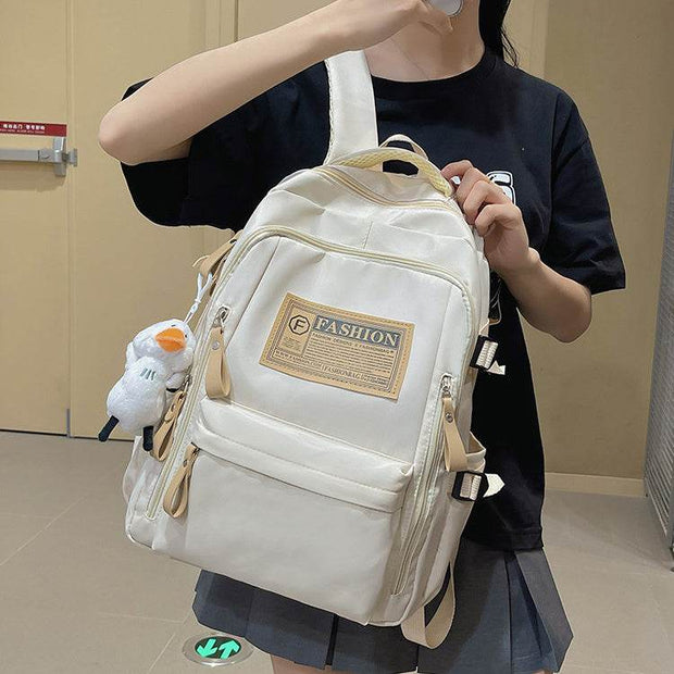 Solid multi-pocket backpack in beige nylon with multiple zippered compartments, suitable for junior high school students and outdoor travel.