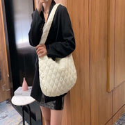 Woman carrying white quilted nylon warm totes shoulder bag with soft handle and zipper closure in modern indoor setting