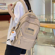 Solid multi-pocket beige nylon backpack for junior high students with large capacity and pendant accessory