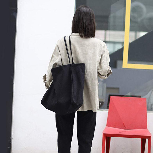 Woman carrying large black canvas shoulder tote bag for shopping outdoors