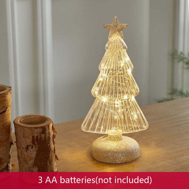 Glittery geometric glass Christmas tree table decoration with warm LED lights on wooden surface